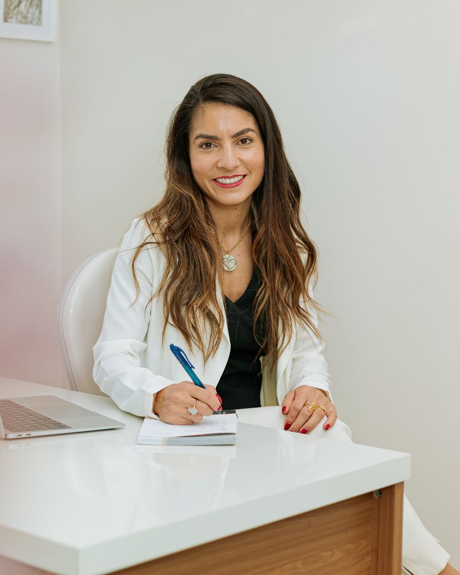 Dra. Cynthia Bessa sorrindo em seu consultório